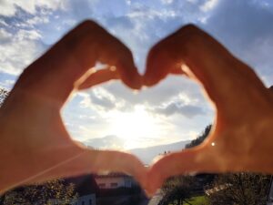 Hände formen ein Herz vor der Sonne als Symbol für Herzkohärenz und geführte Gruppenhypnose in Deutschfeistritz – Ruhe, Selbstheilung und innere Balance.